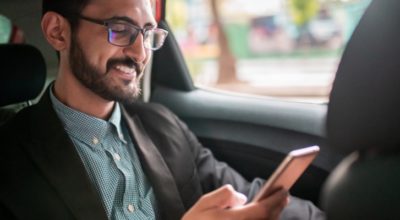 Businessman in the taxi, using a mobile phone on the back seat