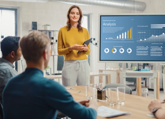 Female Chief Analyst Holds Meeting Presentation for a Team of Economists. She Shows Digital Interactive Whiteboard with Growth Analysis, Charts, Statistics and Data. People Work in Creative Office.