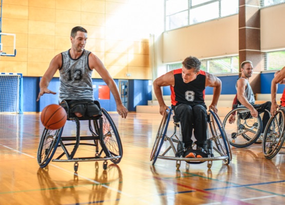 Male wheelchair basketball player dribbling down court against opponent in practice game.