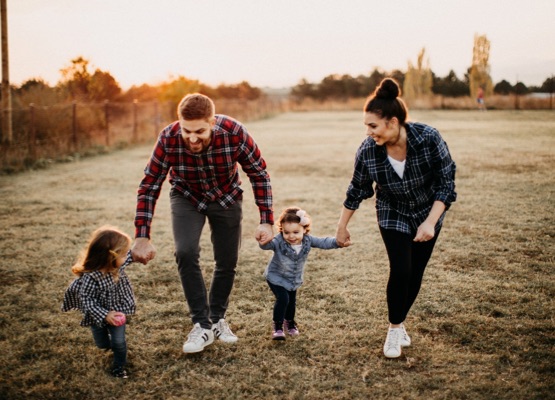 Parents carrying kids, playing on meadow
