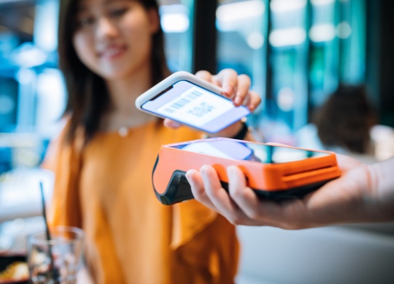 Asian young woman paying with smartphone in a cafe