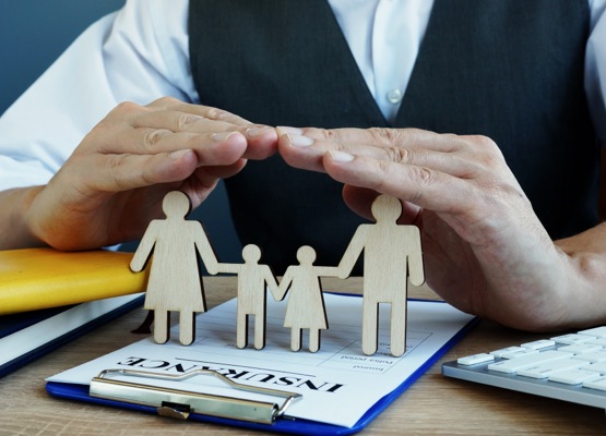 Agent protects family figures. Life Insurance policy on a desk.