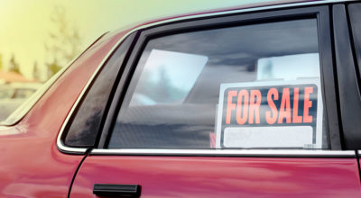 red car with for sale sign in rear passenger window