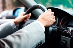 man in suit holding the steering wheel in a car