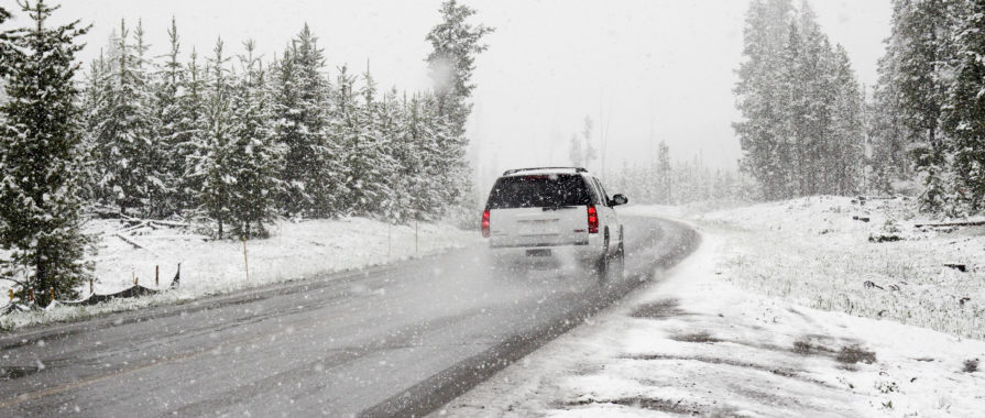 White SUV driving on a road in the winter