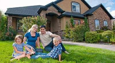 A family sitting outside on grass in front of a brown house