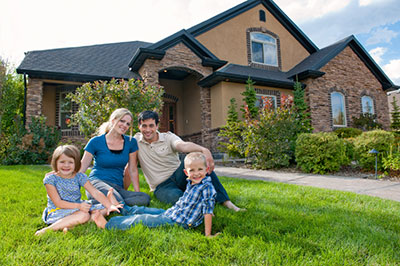 A family sitting outside on grass in front of a brown house