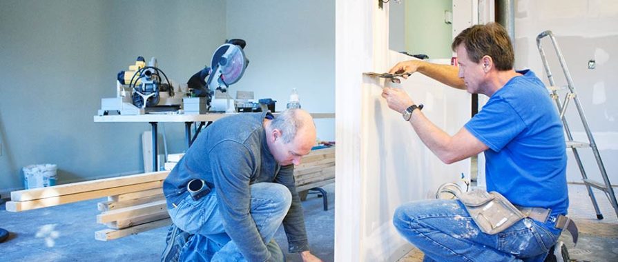 two male contractors working on a wall.